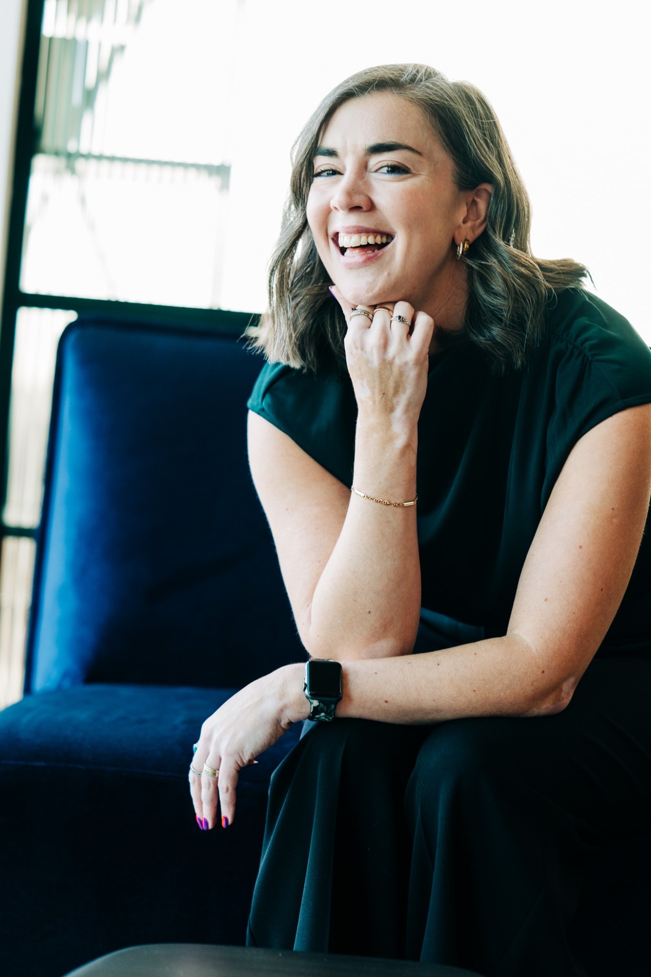 Jancis Dunn smiling, seated on a blue velvet sofa